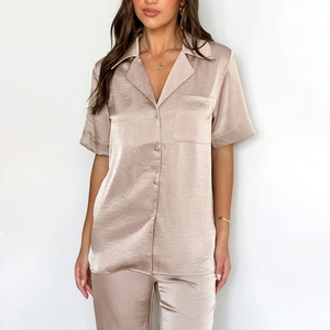 Detail of champagne satin pajama set showing glossy short sleeve shirt and long pants