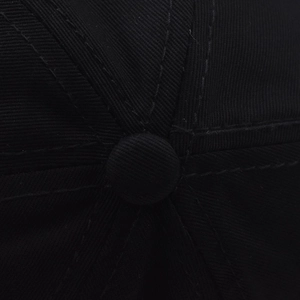 Macro detail of high-quality stitching and top button on a black cotton baseball cap