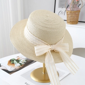 Detailed weave of a cream woven straw hat featuring a matching ribbon and bow accent