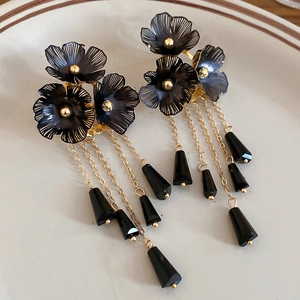 Makroaufnahme von schwarzen Kristallblumen-Ohrringen mit eleganten goldenen Quasten-Anhängern