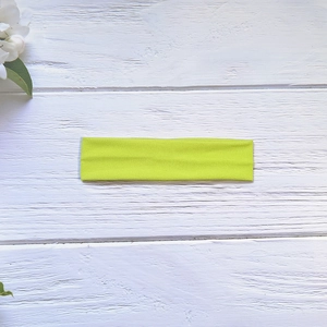 Close-up of fluorescent green high-elastic yoga headband on white wooden background