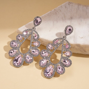 Detail view of镂空 hollow silver earrings with pink teardrop crystals on stone base
