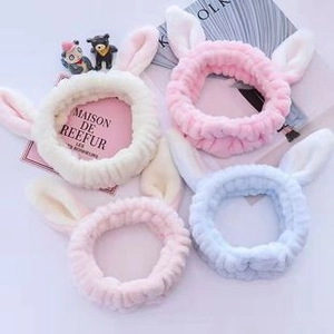 Flat lay of soft plush rabbit ear headbands in white pink and blue on a decorative background