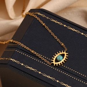 Macro view of 18K gold plated evil eye necklace with turquoise bead on blue jewelry box