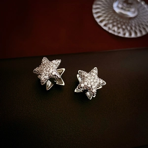 Macro shot of silver star stud earrings with zircon inlay on dark leather background