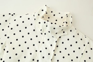 Detailed macro view of white stand collar with black polka dots and fine stitching textures