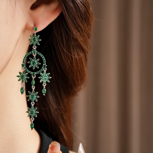 Close-up of elegant green zircon flower earrings with silver tassels on a model