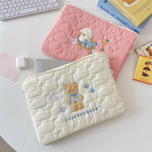 Detalle de fundas acolchadas para portátil con bordados de perro y oso en tela suave