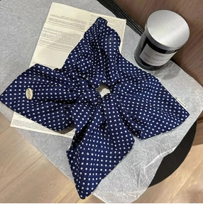 Detail of navy blue polka dot scrunchie with a ribbon bow and elegant cream buckle