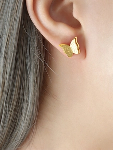 Macro shot of gold butterfly stud earrings with matte texture and polished edges detail