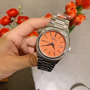 Macro detail of the silver stainless steel band and vibrant orange dial with date display