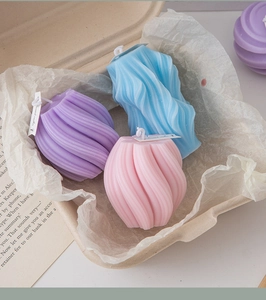 Close-up of spiral and geometric scented candles in pastel purple, pink, and blue