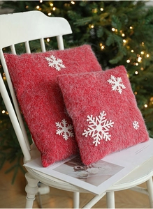 Detail of red Christmas plush pillow with white snowflake embroidery on wooden chair