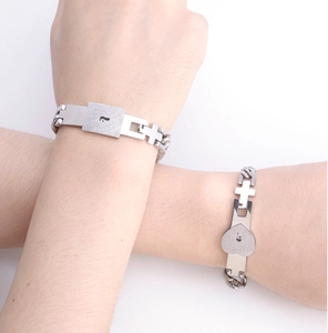 Detail of silver couple bracelets with lock and key charms on intertwined arms