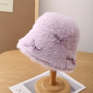 Close-up of purple plush bucket hat featuring three elegant silk bow accents on a stand