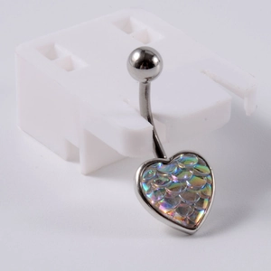 Macro d'un piercing de nombril en acier avec pendentif cœur aux écailles de poisson colorées