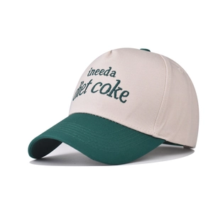 Detail of Diet Coke embroidery on a two-tone beige and green cotton baseball cap