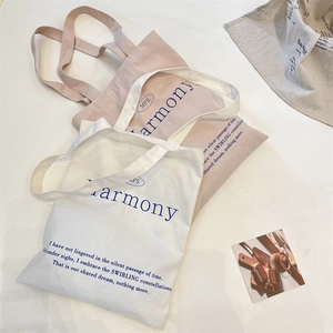 Detail of minimalist canvas tote bags in cream and pink with Harmony literary print