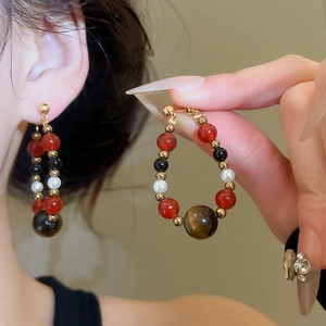 Detail of vintage beaded earrings with tiger eye stone and pearls on gold plated studs