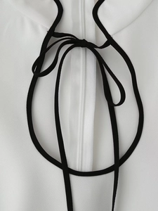 Dettaglio dell'abito bianco con fiocco nero e chiusura lampo invisibile sul retro