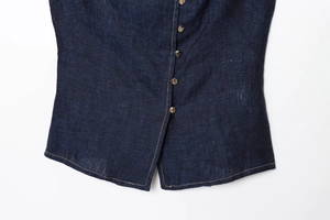 Detail of dark blue denim vest with premium gold metal buttons and woven fabric texture