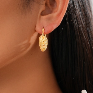 Close-up of heart-shaped hollow earrings in gold finish worn by a model for a chic look