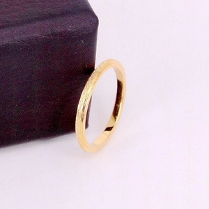 Close-up of golden frosted titanium steel ring placed beside a purple jewelry gift box