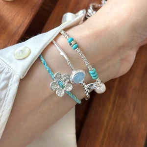 Close-up of S925 sterling silver bracelets with blue woven flowers and turquoise beads