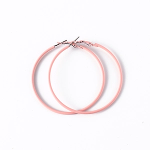 Détail de grandes boucles d'oreilles créoles roses à revêtement mat sur fond blanc