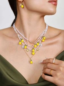 Dettaglio della collana di perline multistrato con margherite, limone e orecchini abbinati