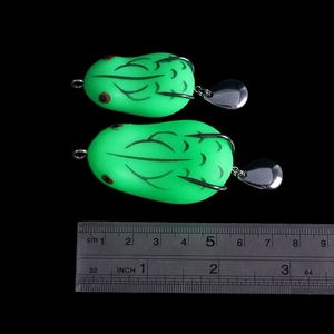 Two 5cm green frog lures with double hooks and spinning sequins shown against a ruler