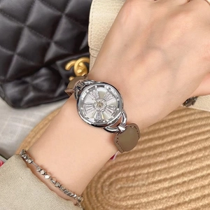 Women's quartz watch with spinning snowflake dial and taupe leather strap worn on wrist