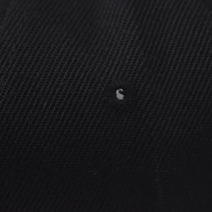 Vue macro du tissu en sergé noir avec œillet de ventilation brodé sur la casquette
