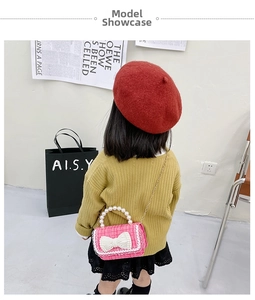 Detailed view of pink woven crossbody bag with white pearl handle and bow for girls
