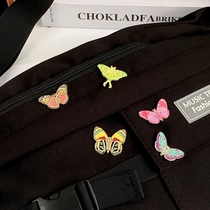 Set of five colorful butterfly enamel pins on black canvas bag with golden metal plating