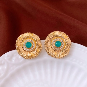 Detail of vintage gold sunflower earring with emerald green stone and zircon accents