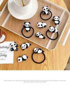 Detail view of cute panda hair clips and elastic ties on a minimalist cream tray