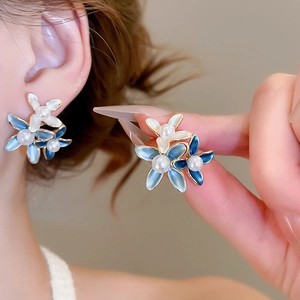Detail of 18K gold plated flower earring with blue enamel petals and pearl center