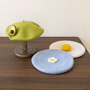 Detailed texture of handmade wool felt berets in avocado, egg, and flower designs