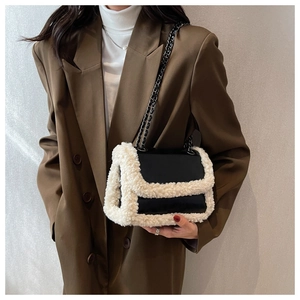Detail of black leather underarm bag with white faux fur trim and metal chain strap