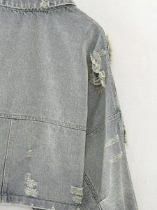 Detail view of distressed light blue denim jacket with vintage ripped holes on back