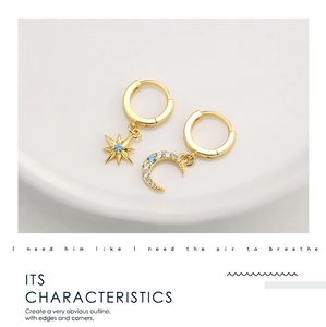 Detailed macro view of gold-tone star and moon earrings with blue zircon inlays