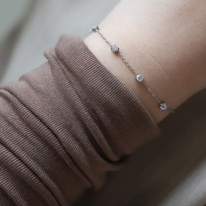 Macro detail of minimalist silver titanium steel bracelet with five sparkling white zircons