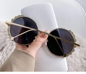 Detaillierte Nahaufnahme der runden Gold-Metall-Sonnenbrille mit gewellten Rändern