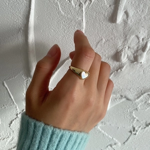 Close-up of golden heart ring with iridescent shell inlay worn on a hand