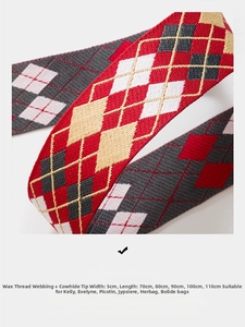Macro detail of 5cm wide woven red and grey plaid bag strap with leather ends