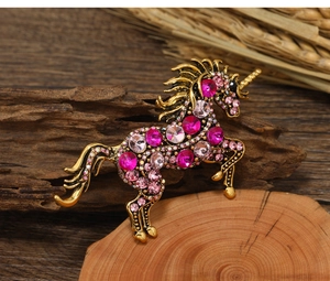 Macro shot of vintage unicorn brooch with pink rhinestones on a rustic wood base