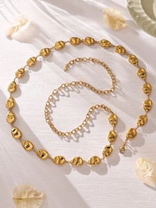 Detailed view of a gold chain belt featuring abstract human face shaped metal links
