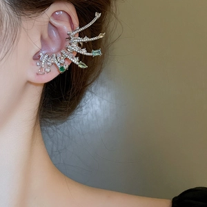 Vue macro d'un earcuff en argent serti de zircons émeraude et clairs sur oreille