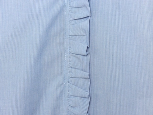 Close-up of blue and white striped cotton poplin fabric with elegant ruffle detail